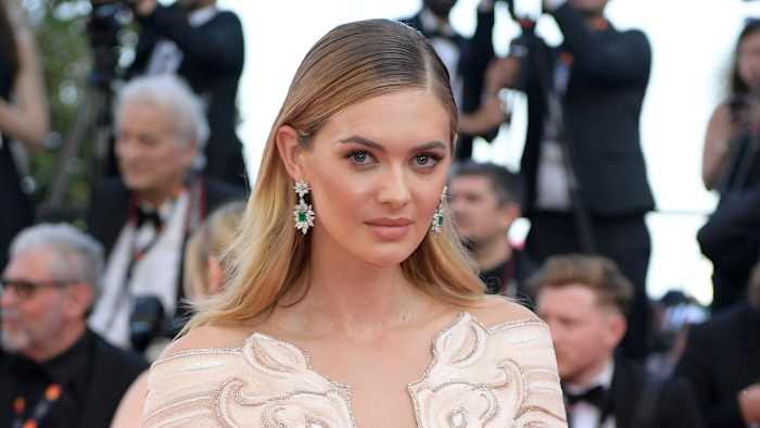 Megan Williams poses in a cream dress with plunging neckline and a slicked-back down-do.